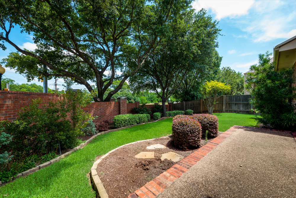    Extended Patio Overlooks Grassy Backyard with Lush Landscaping 